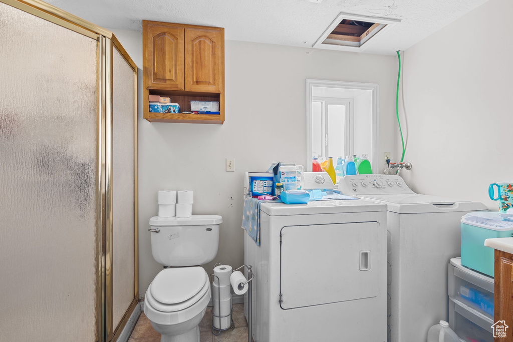 Full bath featuring independent washer and dryer, a stall shower, and toilet