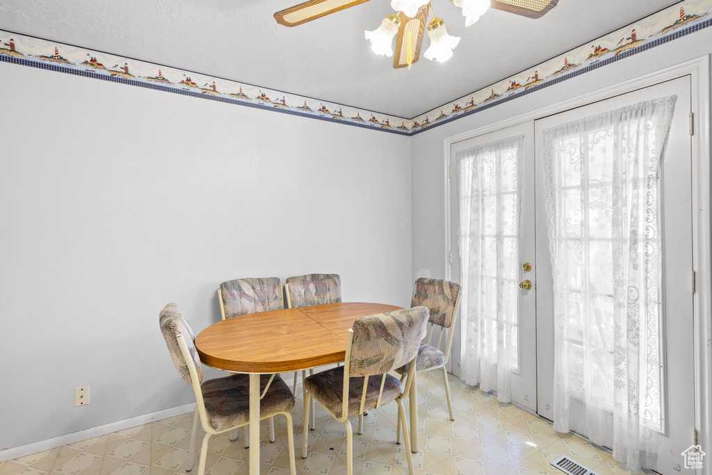 Dining area featuring light floors, baseboards, ceiling fan, and french doors