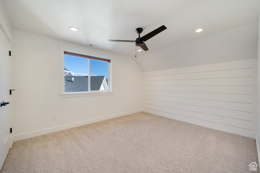 Carpeted spare room with ceiling fan, recessed lighting, baseboards, and vaulted ceiling