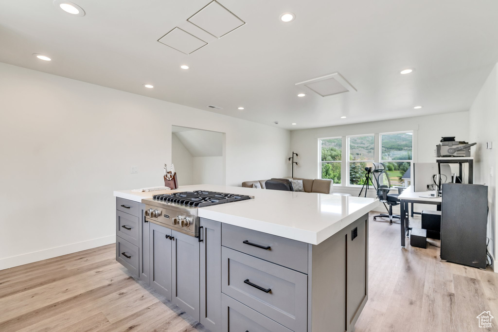 Kitchen with gray cabinetry, stainless steel gas stovetop, light wood-style flooring, recessed lighting, and a kitchen island
