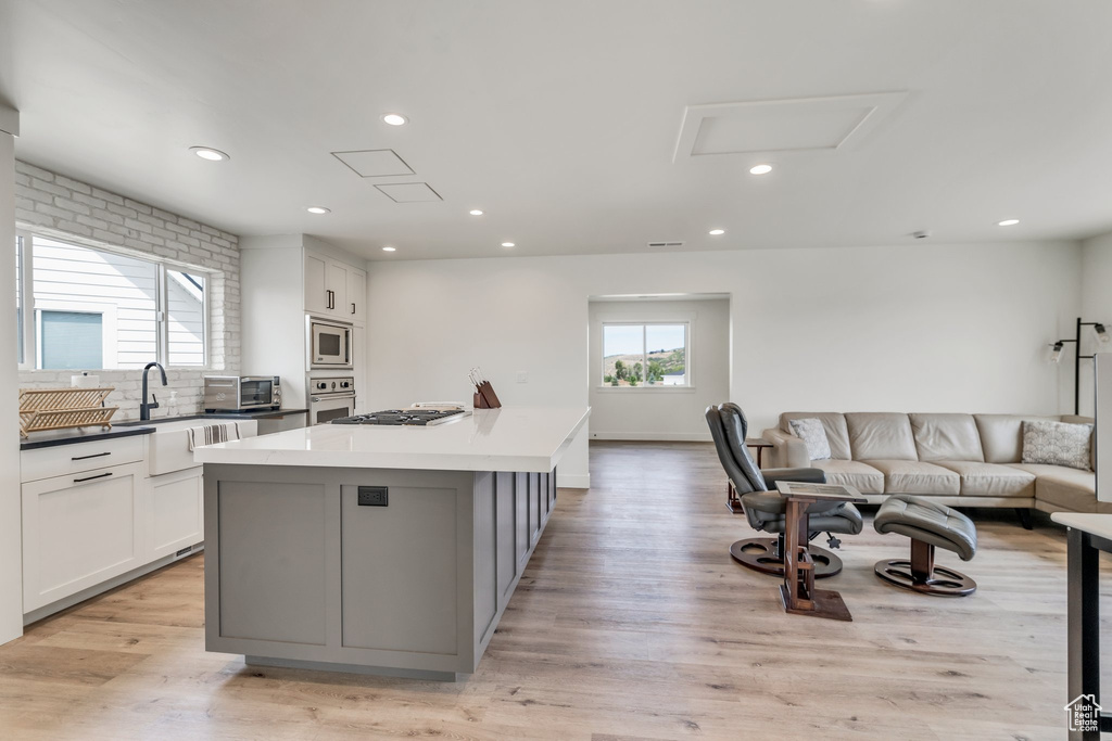 Kitchen with appliances with stainless steel finishes, open floor plan, a kitchen island, white cabinets, and recessed lighting