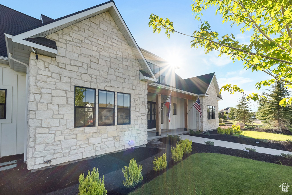 View of front of property with stone siding, a front lawn, and a porch