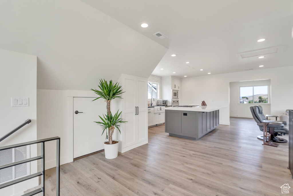 Kitchen featuring plenty of natural light, stainless steel microwave, a center island, light wood-style floors, and recessed lighting