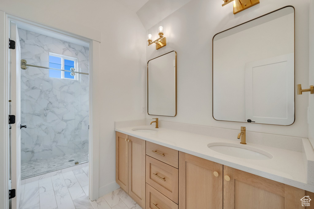 Full bathroom featuring marble finish flooring, a marble finish shower, double vanity, and baseboards