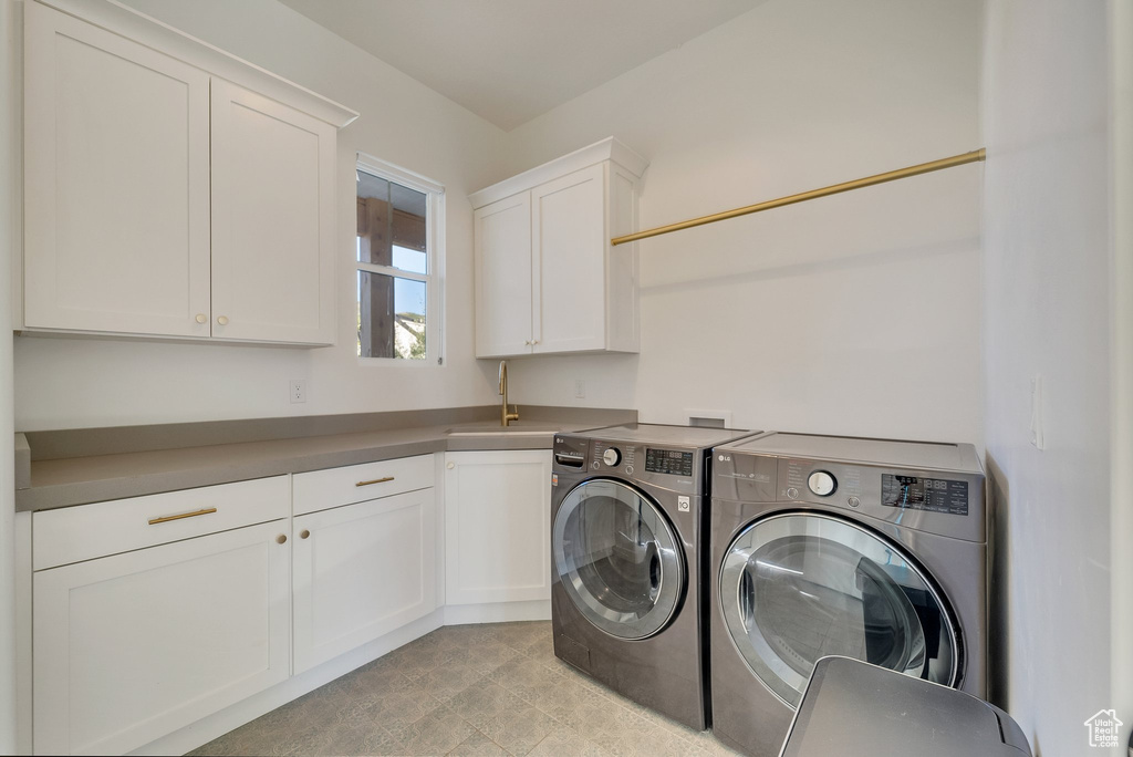 Laundry room featuring washing machine and dryer, cabinet space, and light tile patterned floors