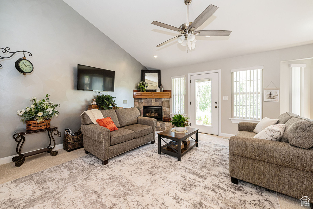 Living room with carpet, baseboards, a fireplace, a ceiling fan, and vaulted ceiling
