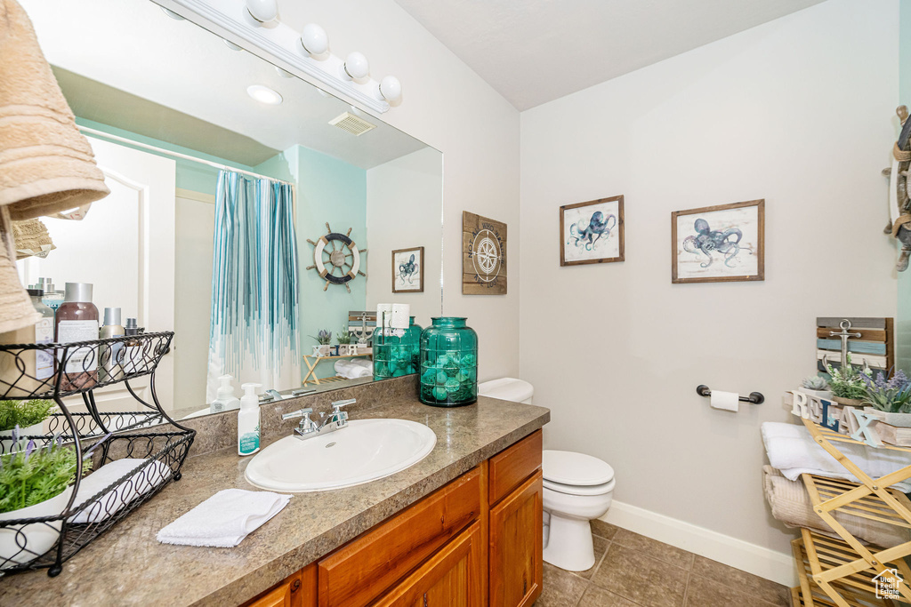 Full bath featuring toilet, vanity, baseboards, tile patterned flooring, and curtained shower
