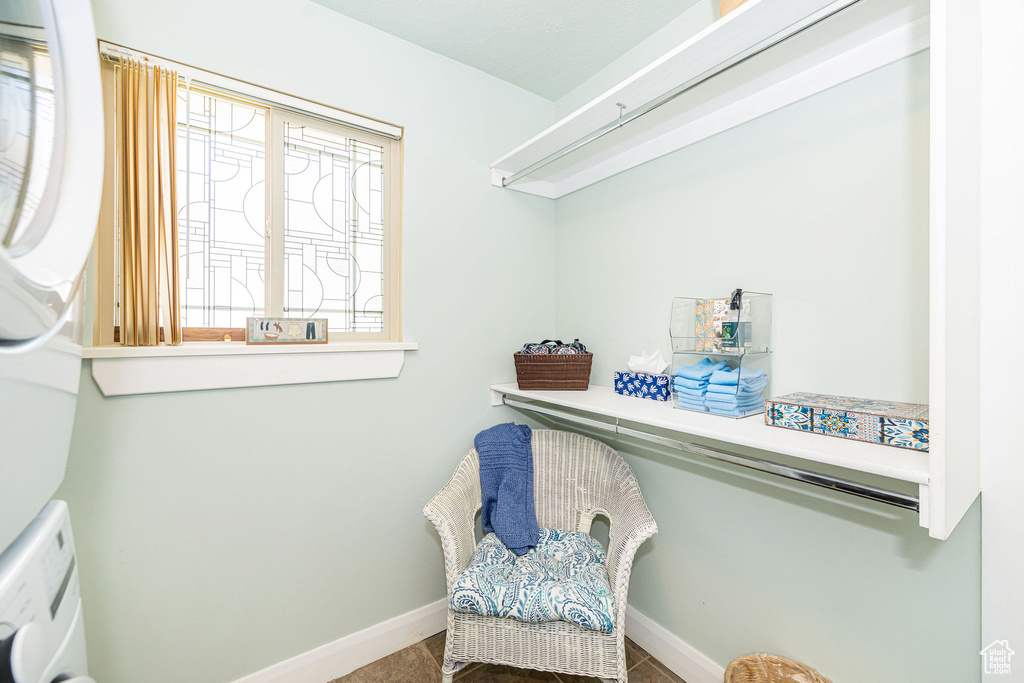 Living area with stacked washing machine and dryer and baseboards