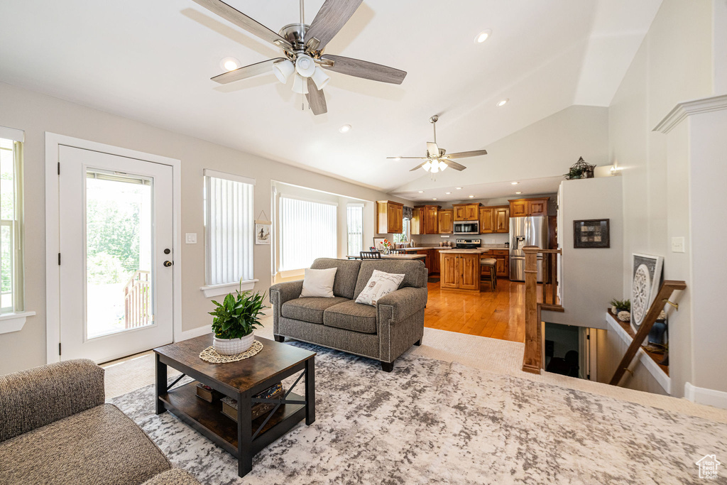 Living area featuring healthy amount of natural light, ceiling fan, vaulted ceiling, light wood finished floors, and recessed lighting