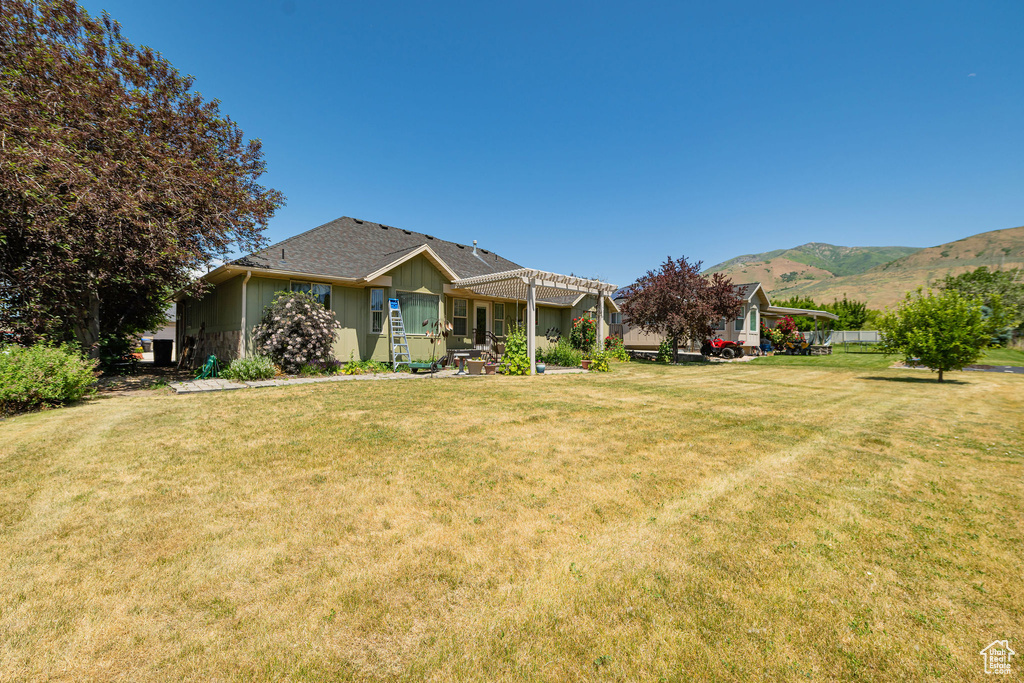 View of front of home featuring a pergola, board and batten siding, a front yard, and a mountain view