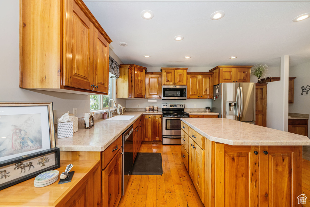 Kitchen with stainless steel appliances, a sink, light countertops, a kitchen island, and recessed lighting
