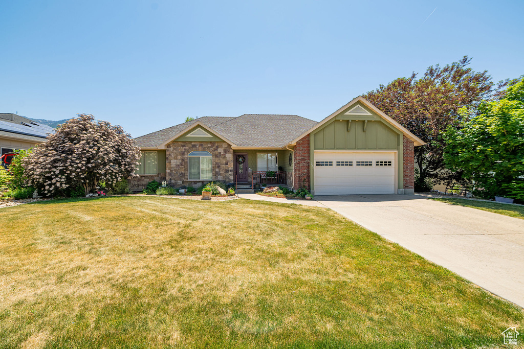 Ranch-style house featuring board and batten siding, a garage, driveway, and a front lawn