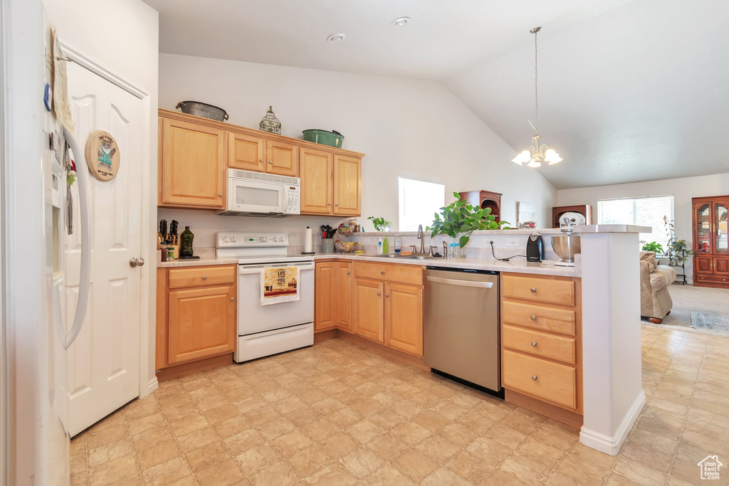 Kitchen featuring white appliances, a peninsula, a sink, light brown cabinetry, and a chandelier