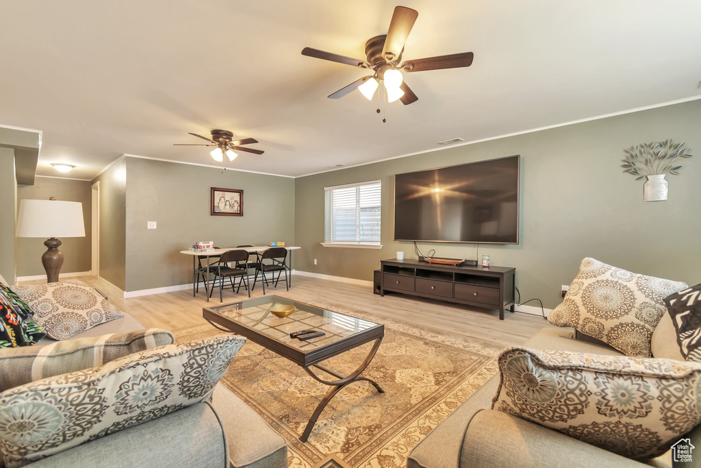 Living area featuring ceiling fan, wood finished floors, ornamental molding, and baseboards