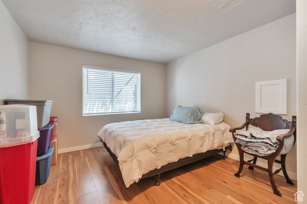 Bedroom featuring light wood-style floors, baseboards, and a textured ceiling