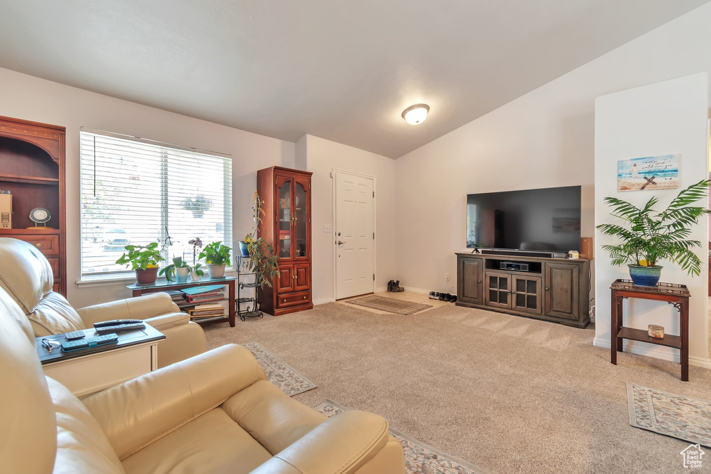 Living room featuring light carpet, baseboards, and vaulted ceiling