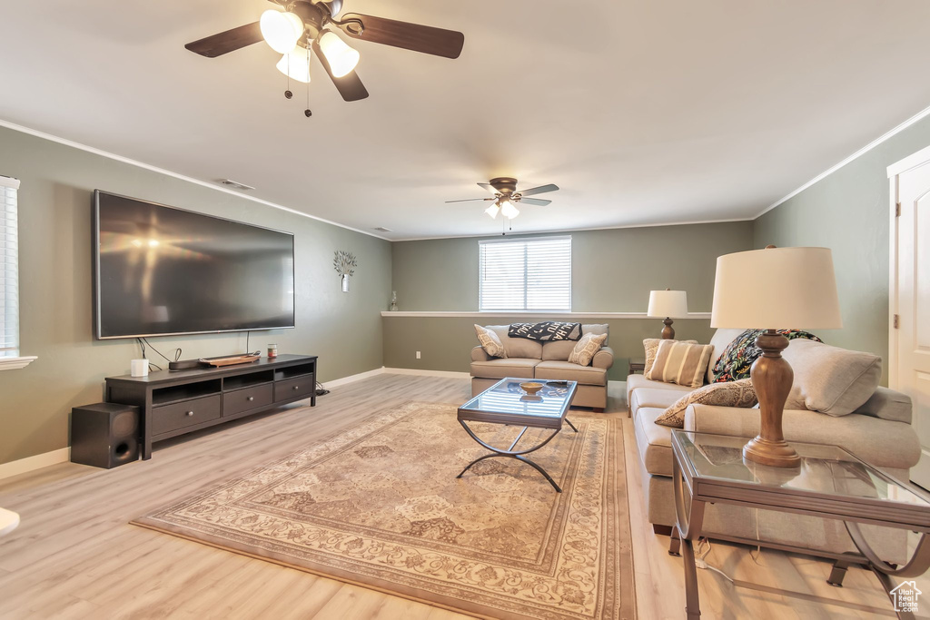 Living room featuring ceiling fan, wood finished floors, crown molding, and baseboards