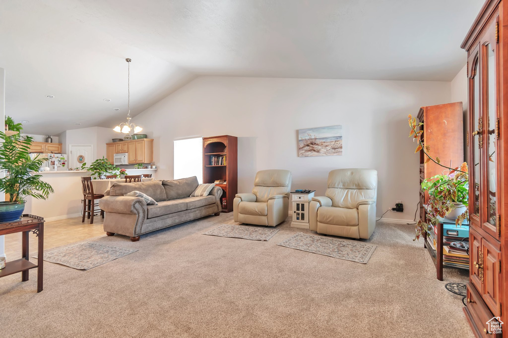 Living area with light carpet, a chandelier, lofted ceiling, and baseboards