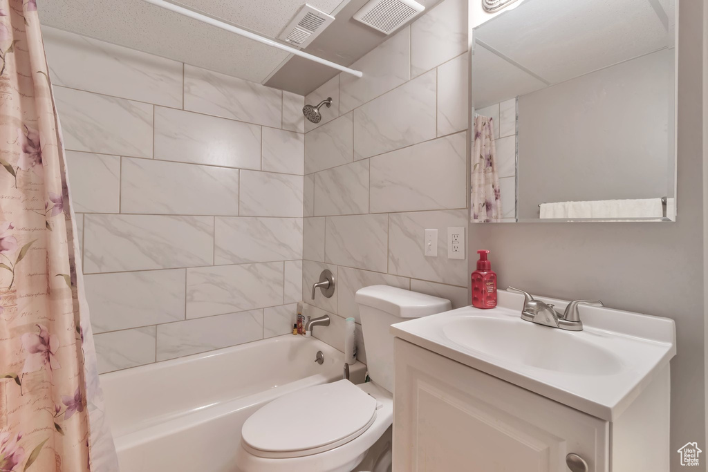 Bathroom featuring shower / tub combo, toilet, vanity, and tile walls