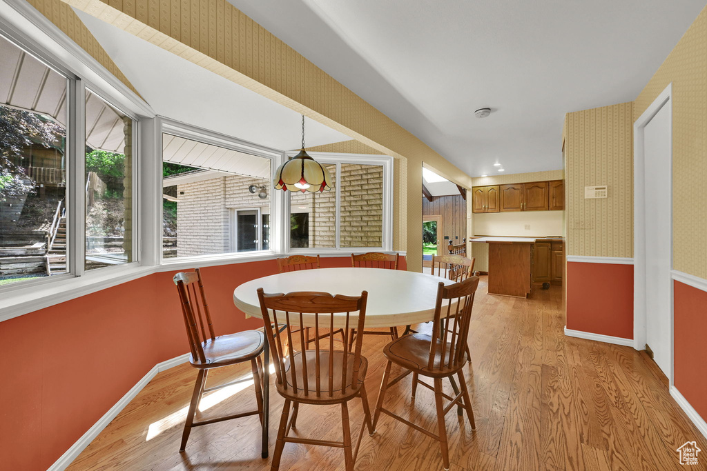 Dining space with light wood finished floors, wallpapered walls, and baseboards