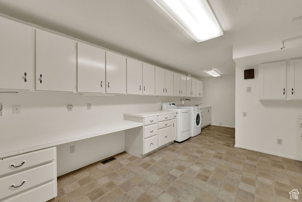 Laundry area featuring cabinet space, washer and clothes dryer, stone finish floors, baseboards, and an office area
