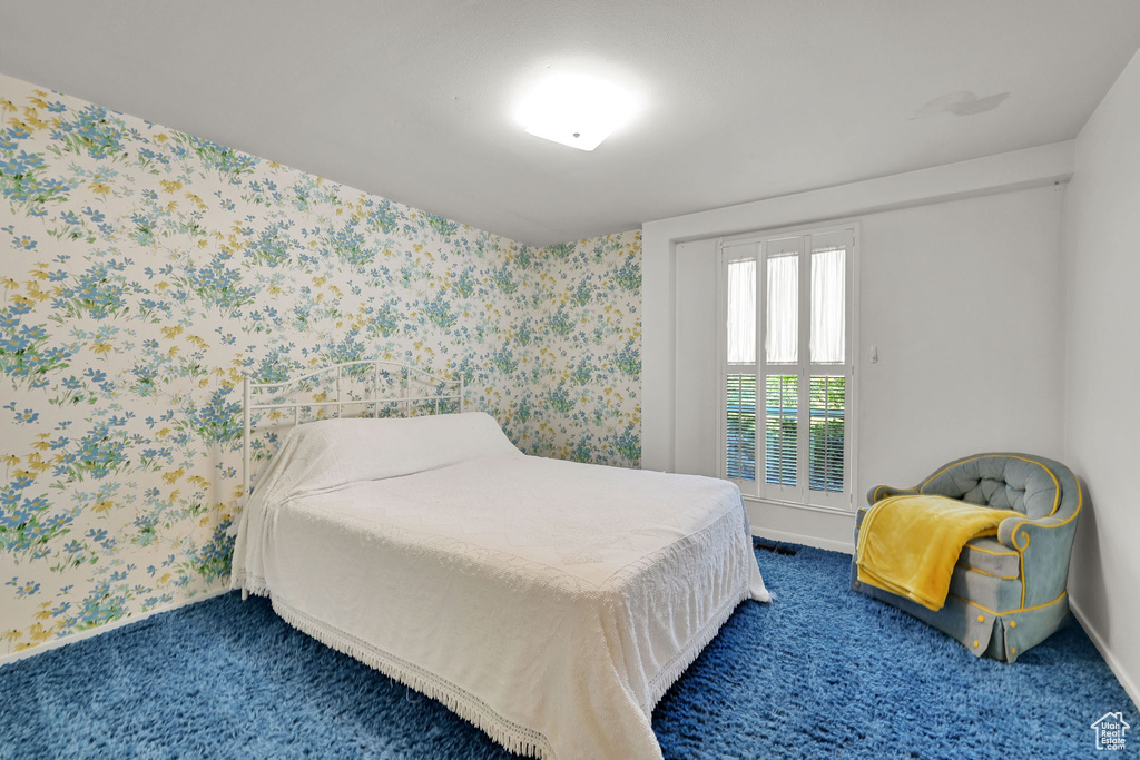 Carpeted bedroom with baseboards and wallpapered walls