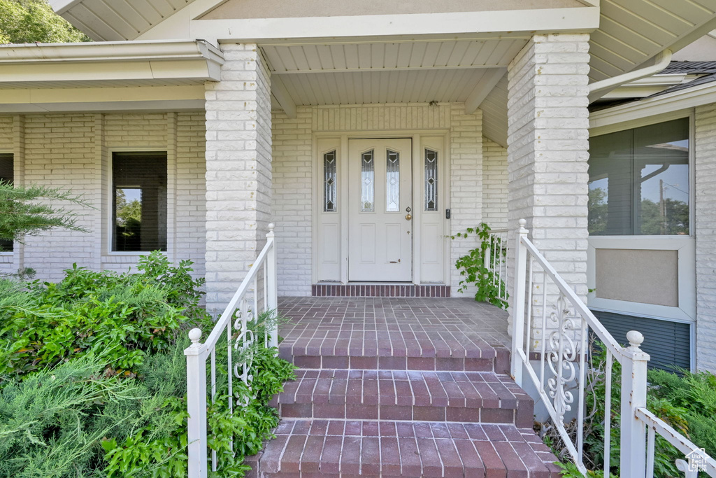Entrance to property featuring brick siding and a porch