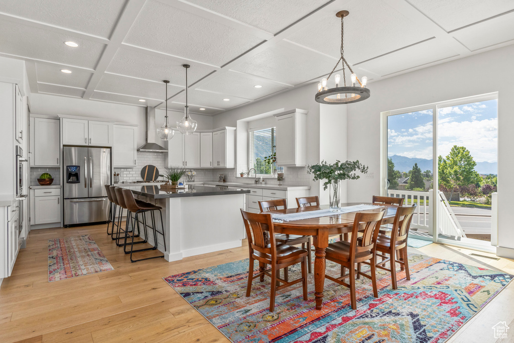 Dining area with coffered ceiling, light wood-style flooring, recessed lighting, and a chandelier