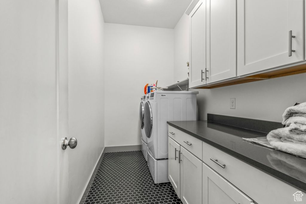 Laundry area featuring washing machine and dryer, cabinet space, and baseboards
