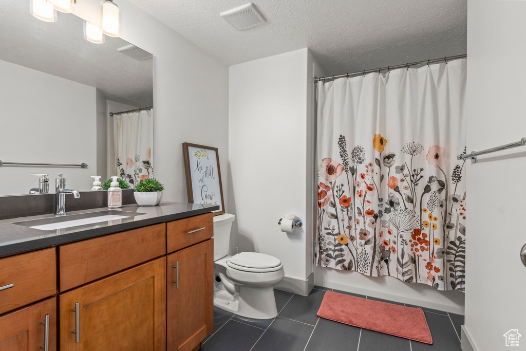 Full bath with vanity, toilet, tile patterned floors, a textured ceiling, and shower / bath combo with shower curtain