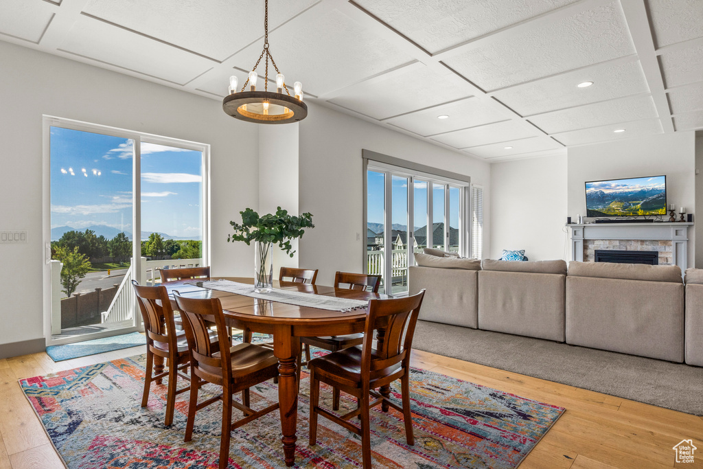 Dining area with coffered ceiling, light wood-style flooring, recessed lighting, a fireplace, and a chandelier