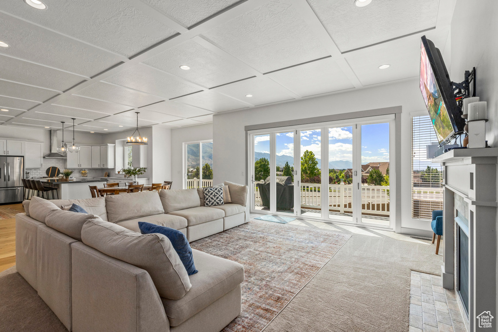 Living area with recessed lighting, coffered ceiling, a fireplace, a chandelier, and light carpet