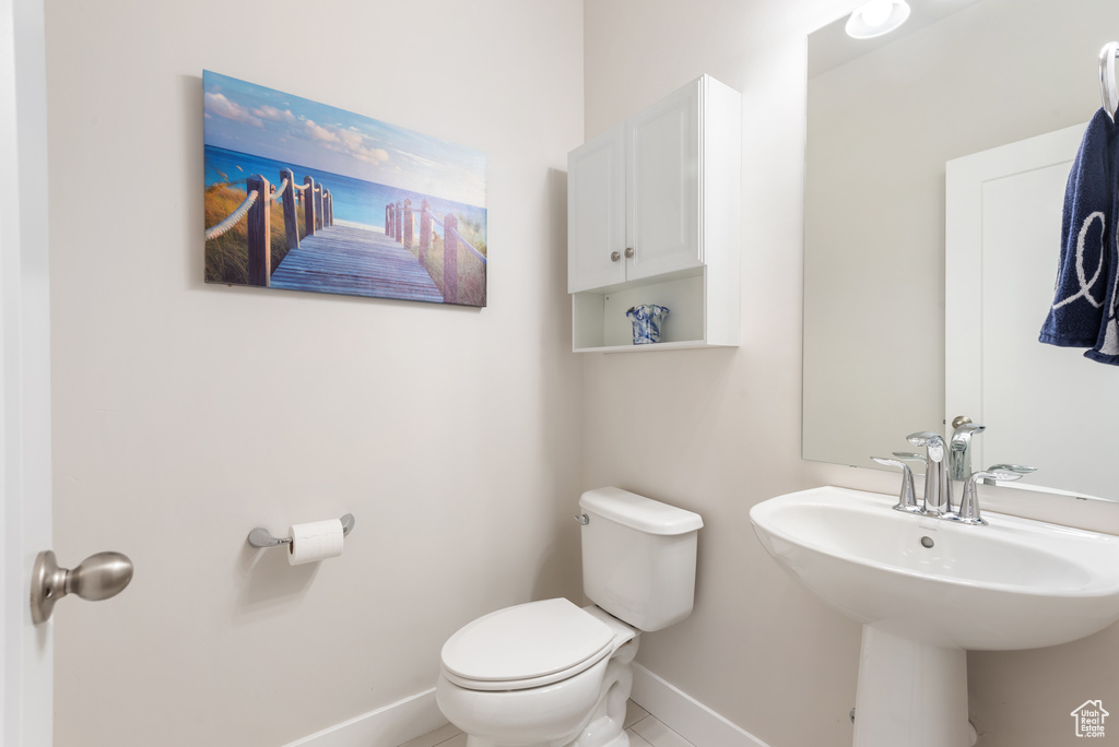 Half bathroom with baseboards, toilet, and a sink
