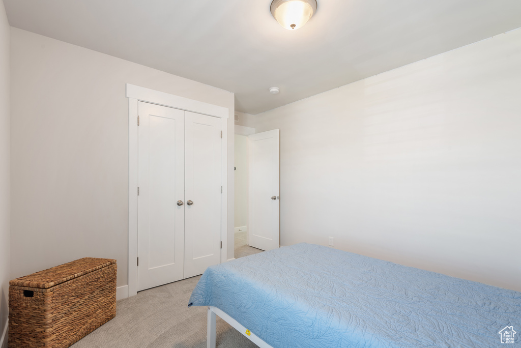 Bedroom with light carpet, a closet, and baseboards