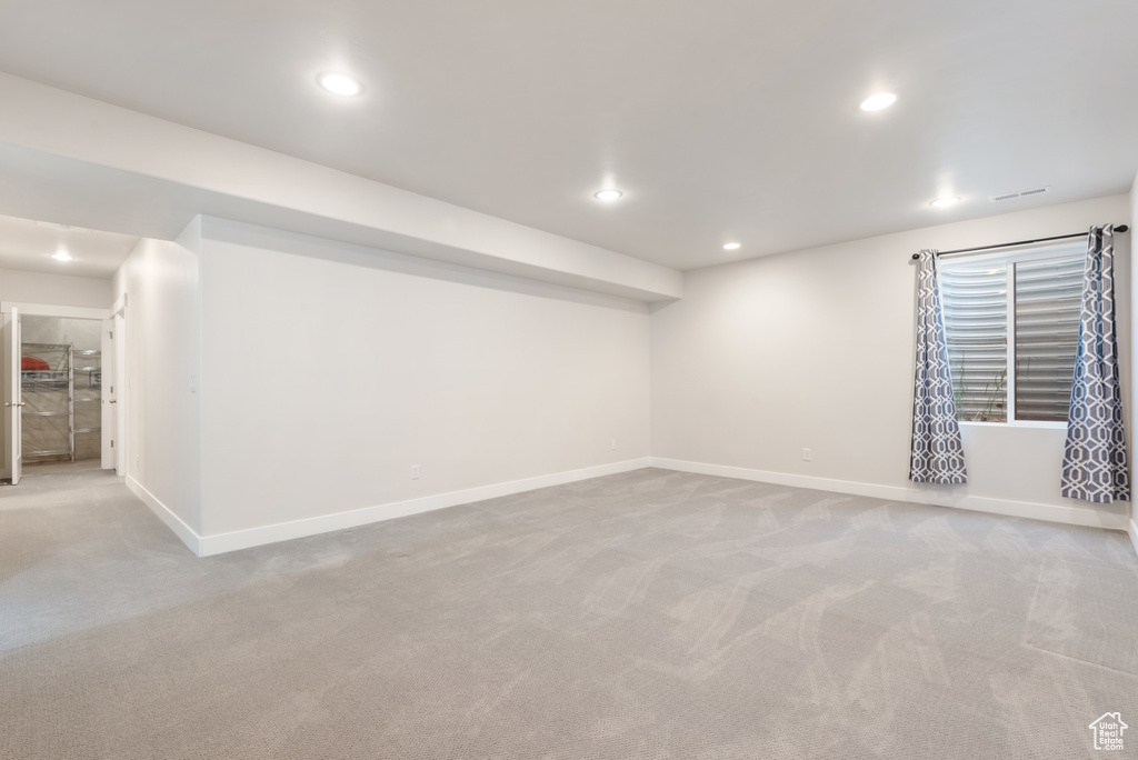 Finished below grade area featuring light colored carpet, recessed lighting, and baseboards