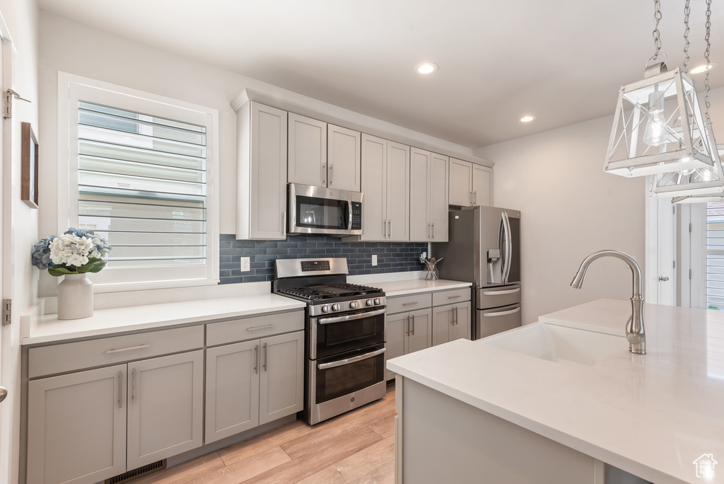 Kitchen with stainless steel appliances, gray cabinets, tasteful backsplash, recessed lighting, and light wood finished floors