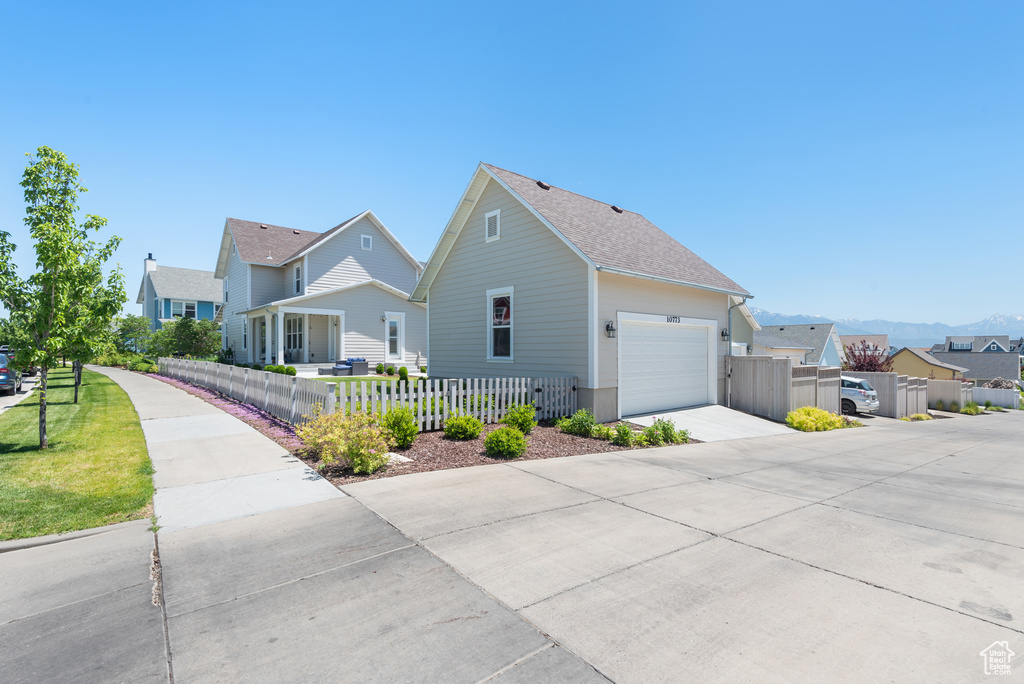 View of side of property with driveway, a residential view, roof with shingles, and a garage