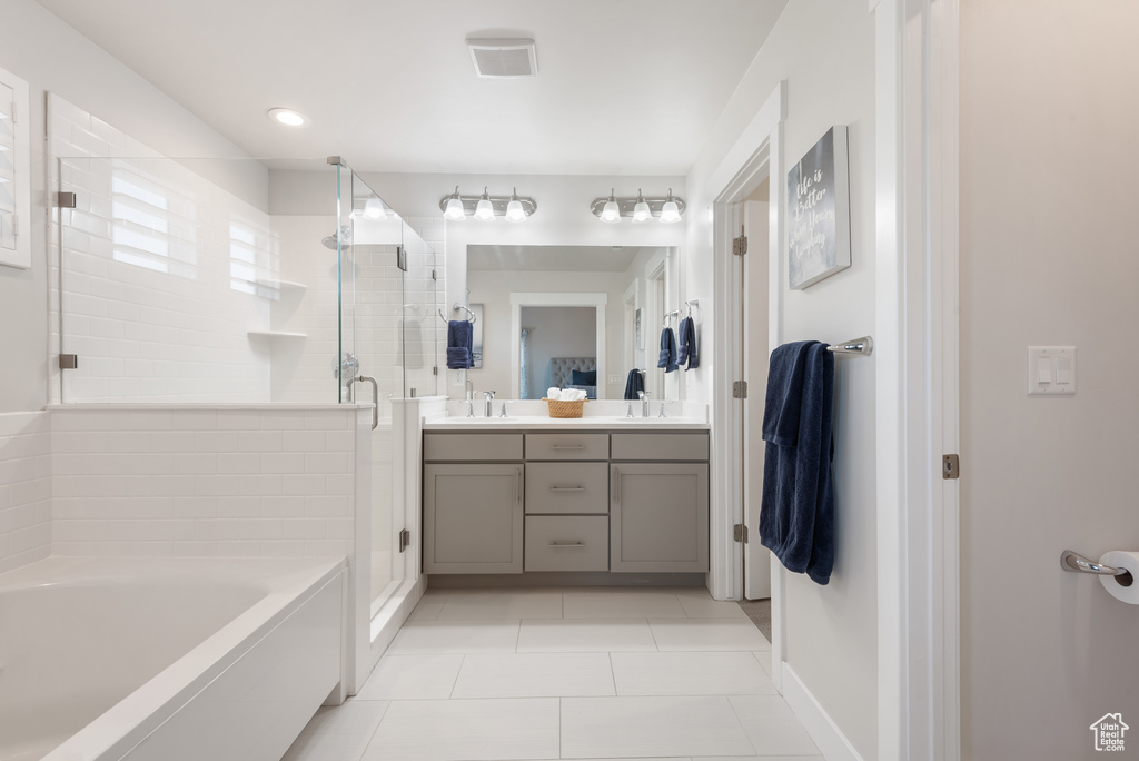 Bathroom featuring double vanity, a stall shower, tile patterned flooring, a garden tub, and baseboards