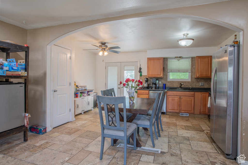 Dining area with stone tile floors, arched walkways, and a ceiling fan