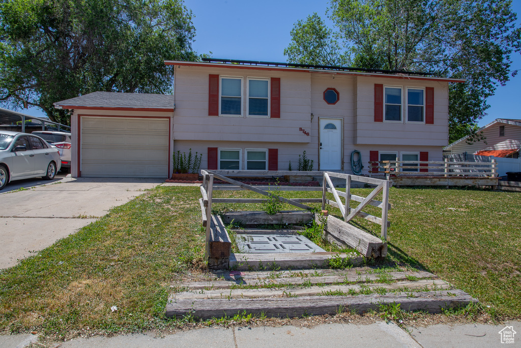 Bi-level home featuring an attached garage, driveway, and a front lawn