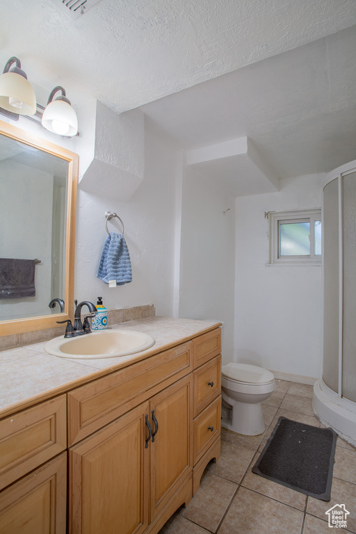 Bathroom with a shower stall, vanity, toilet, tile patterned flooring, and a textured ceiling