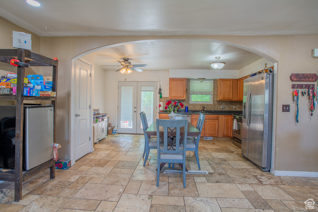 Kitchen with stainless steel appliances, arched walkways, stone tile flooring, a sink, and dark countertops