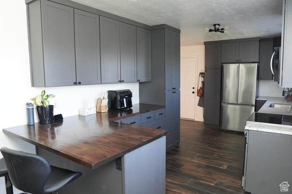 Kitchen featuring appliances with stainless steel finishes, a peninsula, dark wood-style floors, wooden counters, and a sink