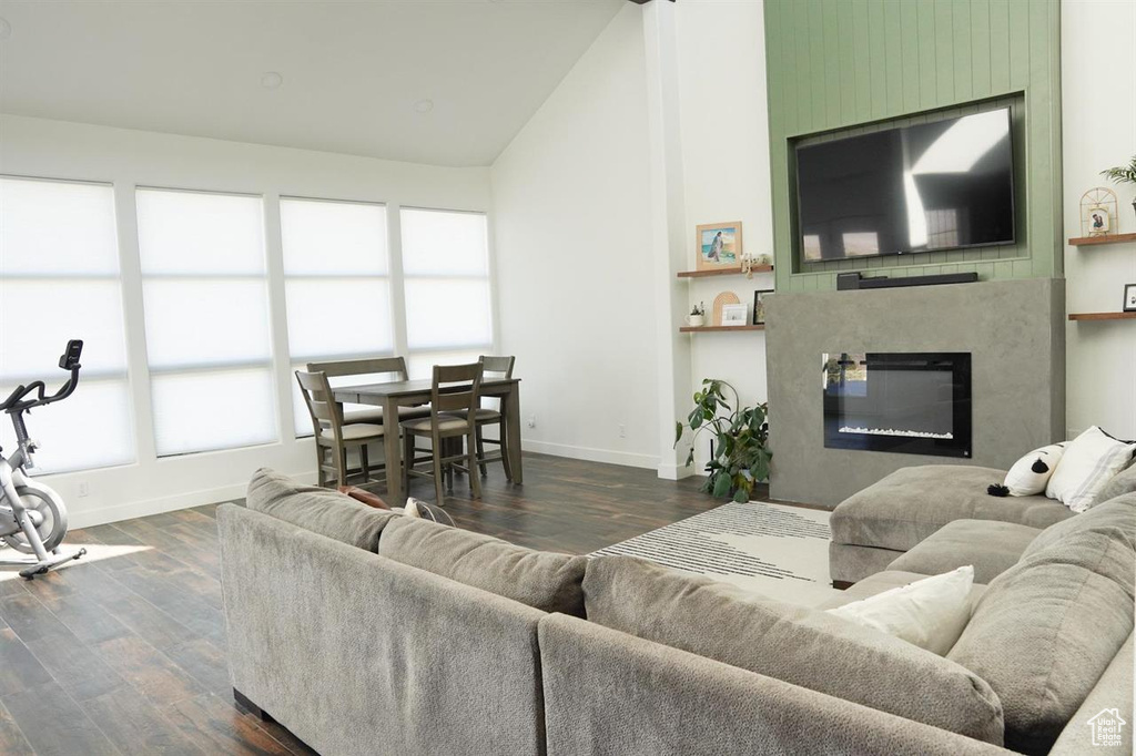 Living area with baseboards, dark wood-style flooring, lofted ceiling, and a fireplace