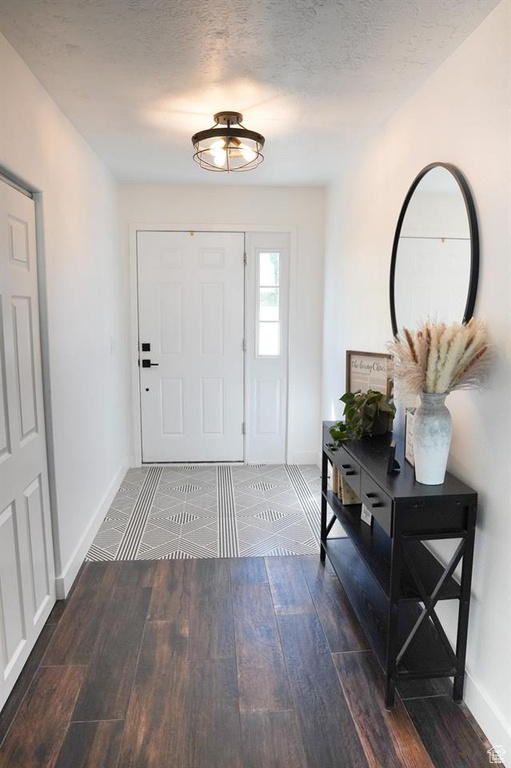 Foyer with baseboards and wood finished floors