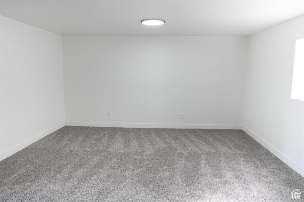 Carpeted spare room featuring baseboards