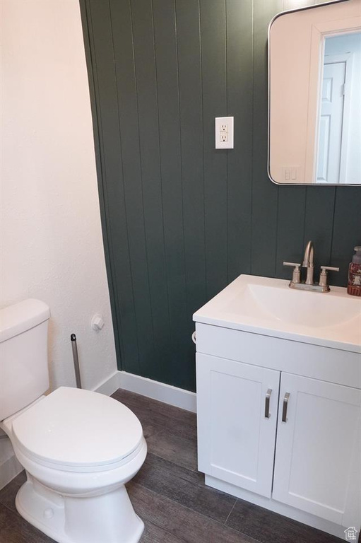 Bathroom featuring vanity, toilet, wood finished floors, and baseboards