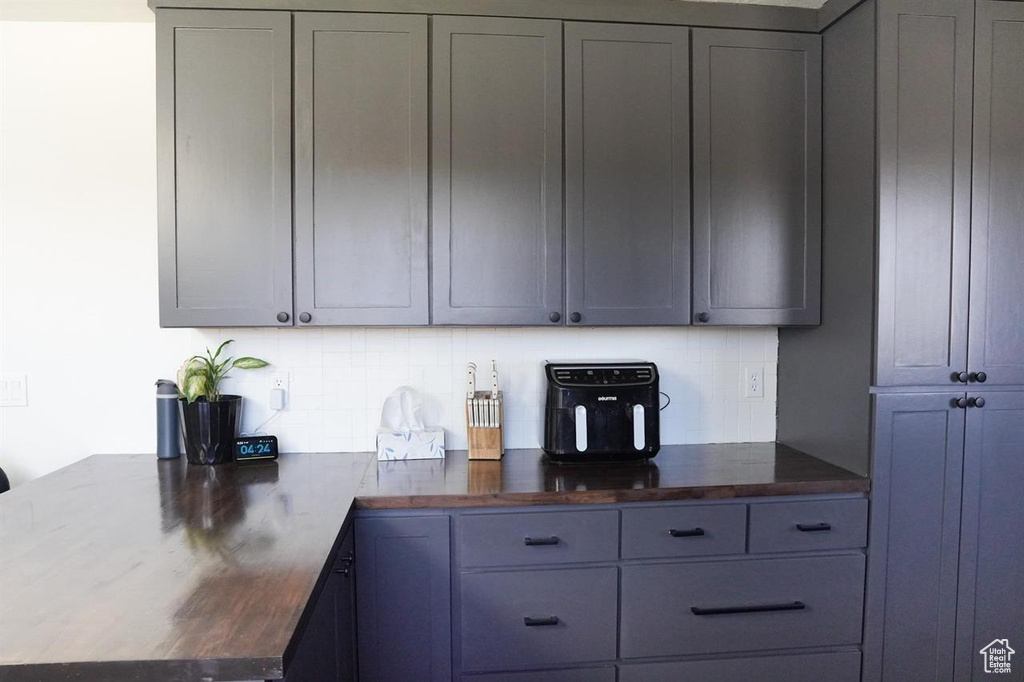 Kitchen with tasteful backsplash, a peninsula, gray cabinetry, and butcher block countertops