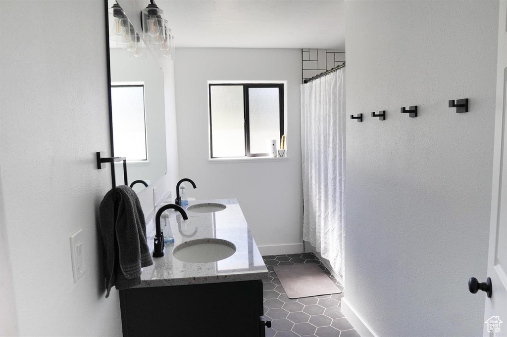 Bathroom featuring double vanity, baseboards, a shower with curtain, and tile patterned flooring