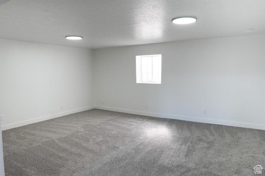 Empty room with carpet flooring, baseboards, and a textured ceiling